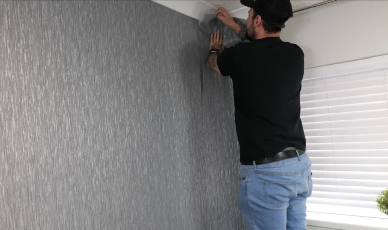 Installer smoothing a large grasscloth panel against the wall in a Denver home