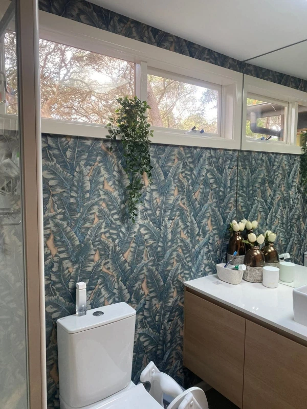 Blue-green botanical palm leaf wallpaper installed in a Denver powder room above a floating timber vanity