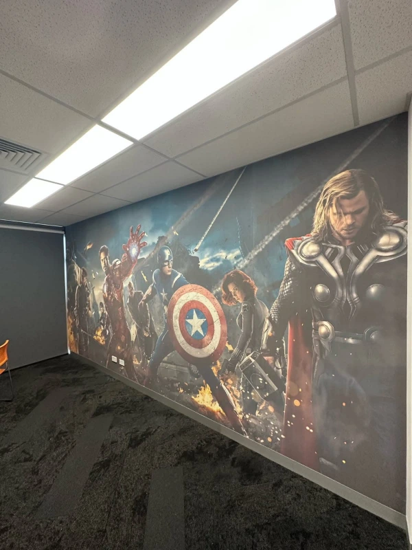 Large-format superhero wall mural covering a full feature wall in a Denver commercial office