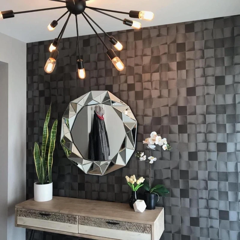 Charcoal geometric 3D-panel wallpaper on an entryway accent wall in a Denver home, with a sputnik chandelier and faceted round mirror