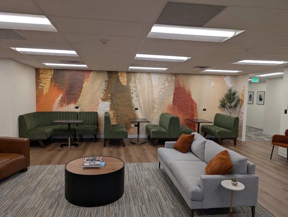 Abstract painted mural wallpaper in warm rust and cream tones across an office lounge wall in Denver